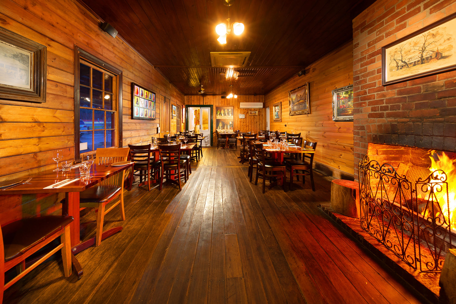 The Front Dining room of the restaurant with tables, chairs, and a fireplace.