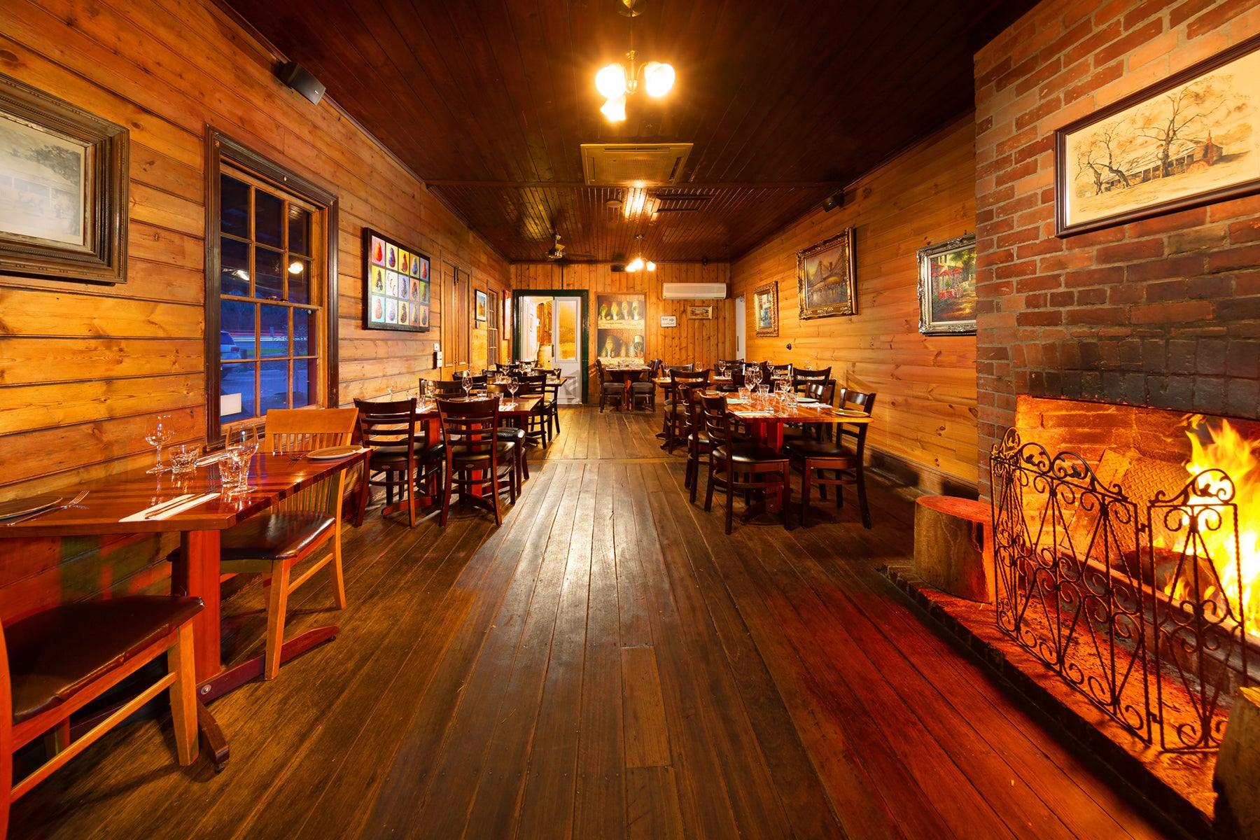 The Front Dining room of the restaurant with tables, chairs, and a fireplace.