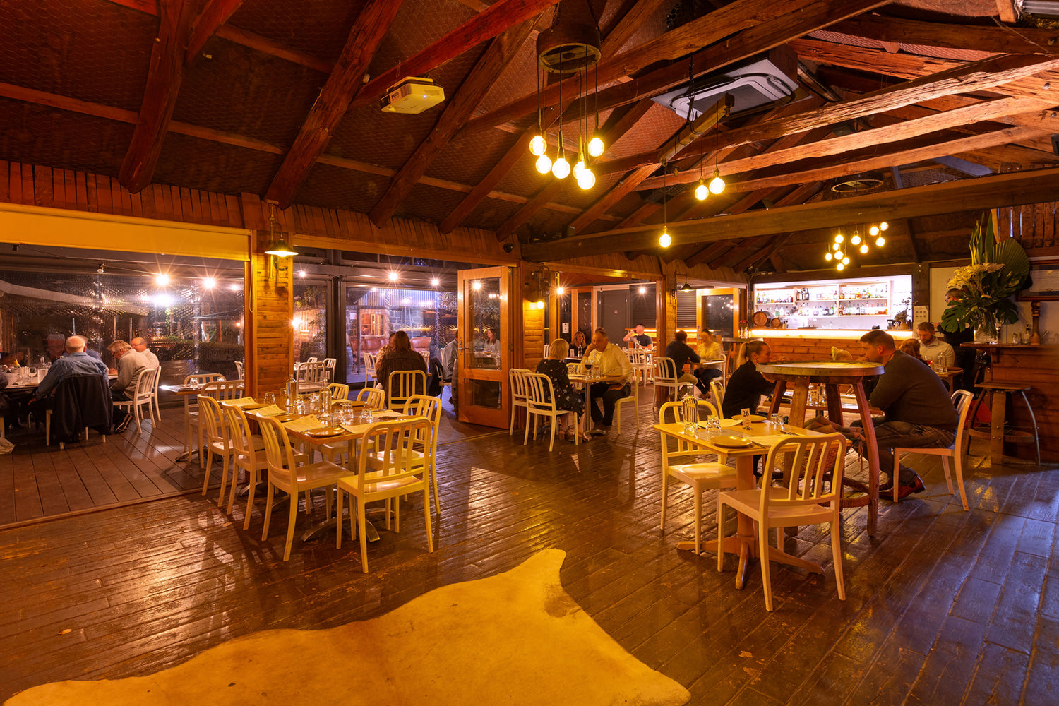 Bar area with wooden tables and chairs in a rustic setting.